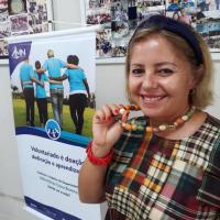 Participante mostrando o colar feito durante a Oficina de Bijuterias